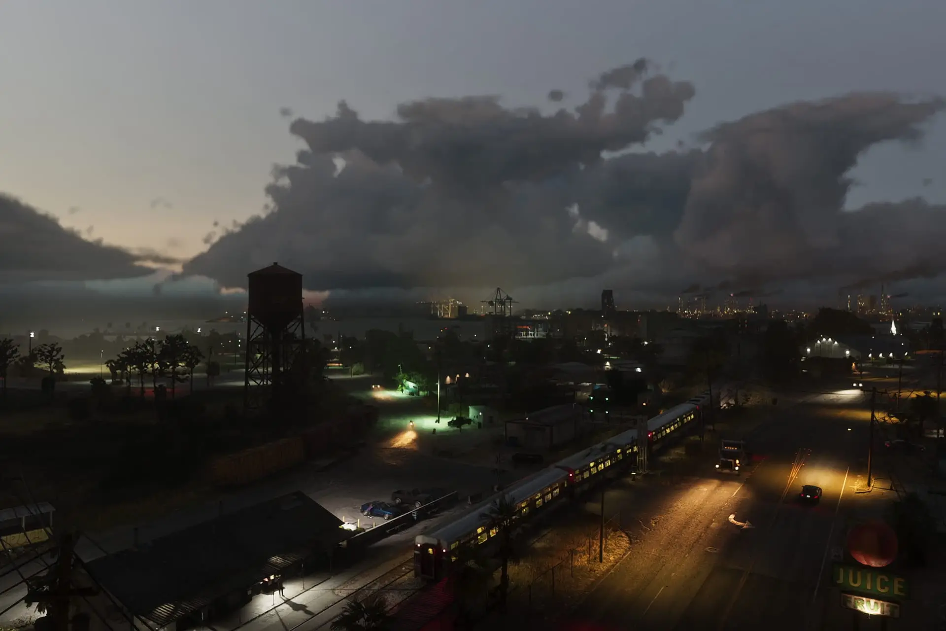 Vista al atardecer de una ciudad con un tren elevado, un tanque de agua, luces de calle encendidas y un letrero Juice junto a una avenida amplia.