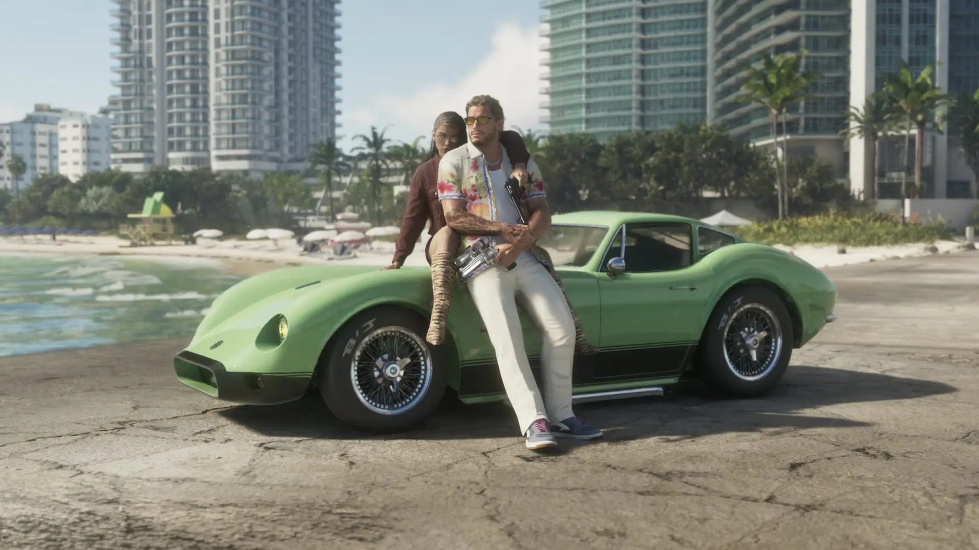 Two men in colorful shirts sit on a green sports car on a beach promenade, with high-rise hotels and umbrellas behind.